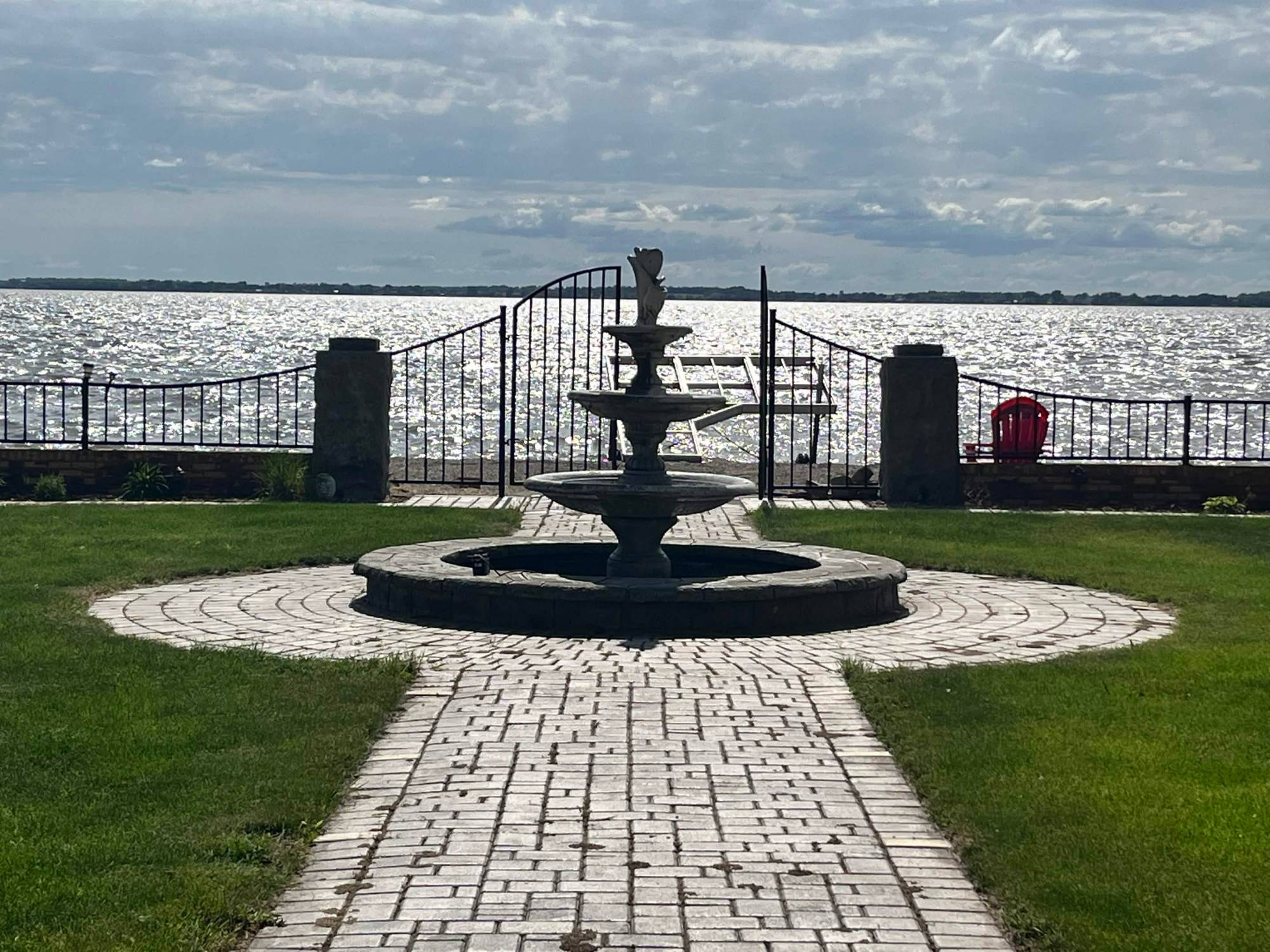 Brick path and three-tier fountain leading to a gated opening onto Lake Kampeska