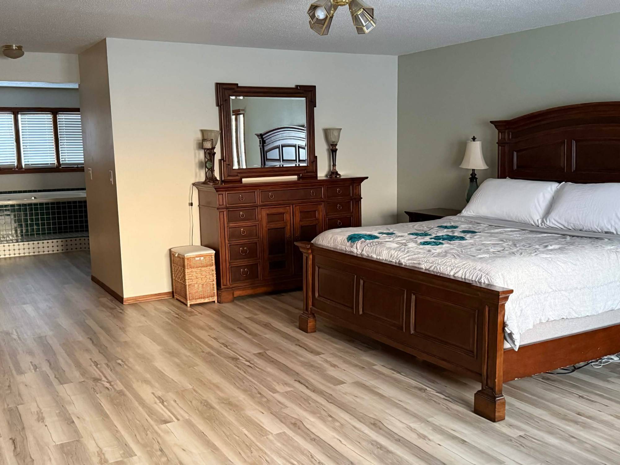 Primary suite dresser with jetted tub beyond